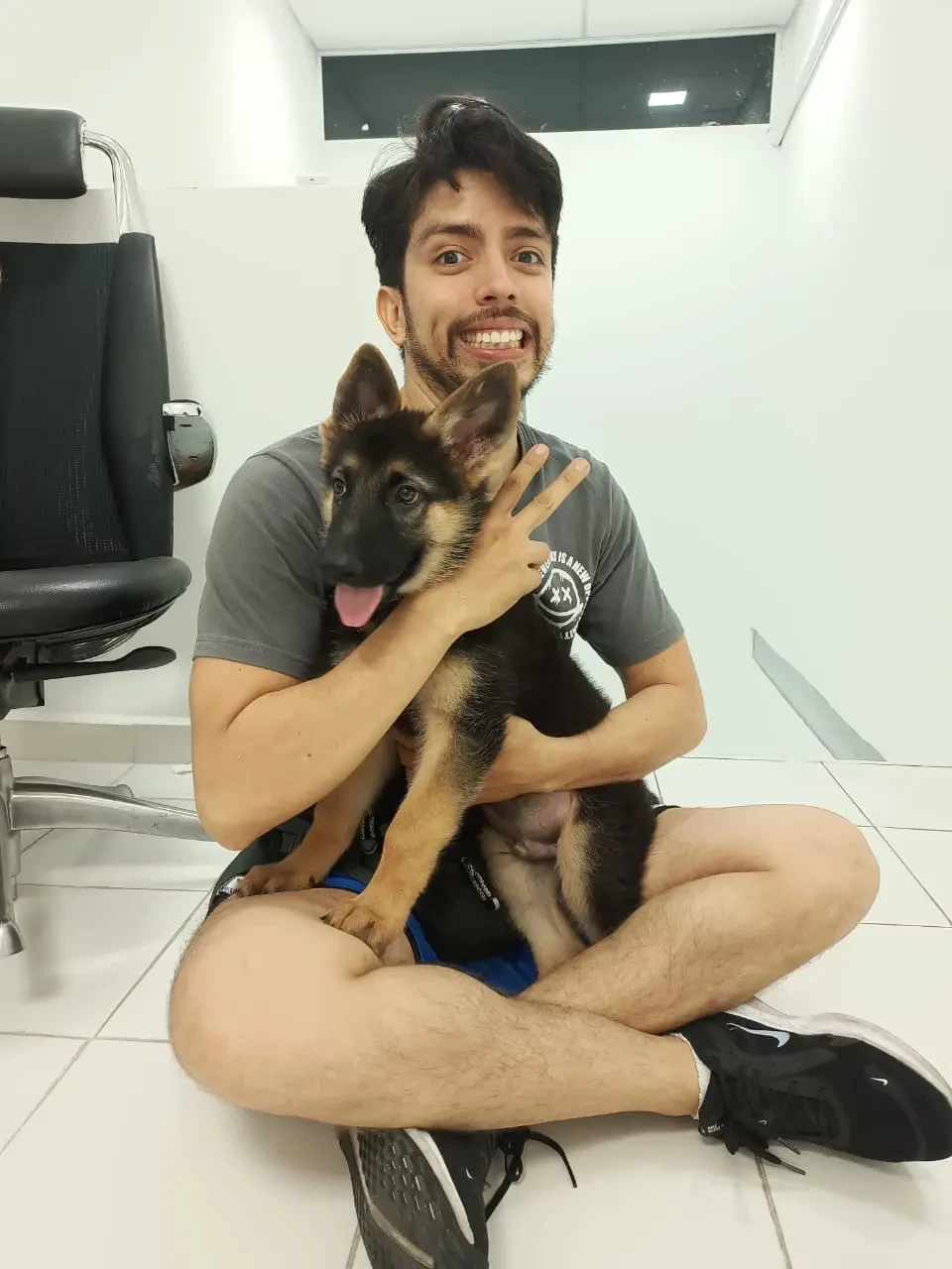 Rafael Cuevas sitting on the floor holding his German Shepherd puppy